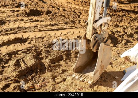 L'attrezzatura della pala retroescavatore, utilizzata sul retroescavatore per spostare terreno o ghiaia, poggia sullo sporco in un cantiere edile. Foto Stock