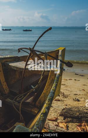 Un luminoso sciistico giallo poggia sulla sabbia bianca di una spiaggia. Le acque blu calme lambiscono dolcemente sulla riva. Il cielo è limpido e luminoso. Foto Stock