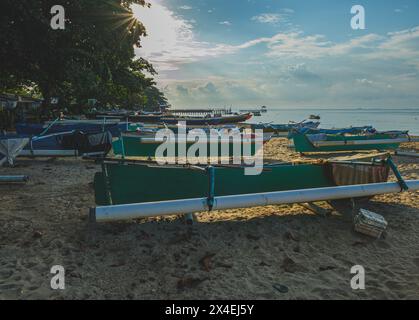 Balikpapan, Indonesia - 16 aprile 2024. Molte colorate barche da pesca in legno vengono tirate su una spiaggia sabbiosa al mattino. Foto Stock