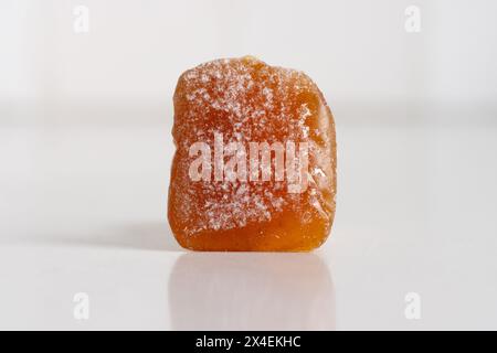 una caramella allo zenzero gommosa, stropicciata con zucchero a velo su sfondo bianco, chiudi macro con spazio di copia Foto Stock