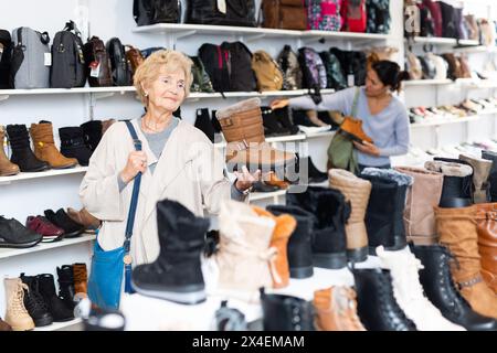 Donna europea matura sceglie stivali invernali Foto Stock