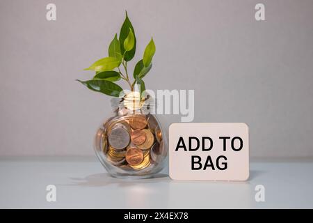 La mano tiene un telefono con l'iscrizione ADD TO BAG sullo schermo rosso, su sfondo nero. Foto Stock