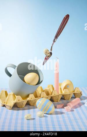 Decorazione concetto pasquale con uova, candela, tazza in ceramica e blister decorati su sfondo azzurro. Idee creative per la pubblicità. Vista frontale Foto Stock