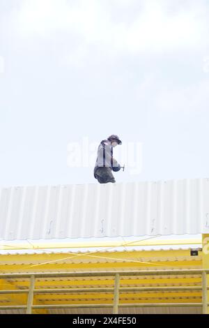 Un uomo sta lavorando in cima ad un alto edificio con un cielo limpido Foto Stock