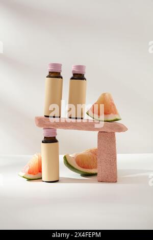 Sfondo creativo minimalista per la presentazione di cosmetici o prodotti con ingredienti di pomelo. Tre bottiglie di medicinali senza etichetta decorate con Foto Stock