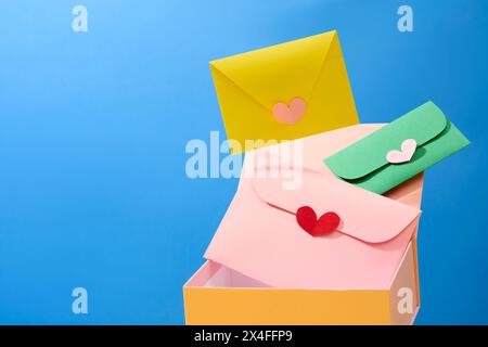 La vista frontale di una confezione regalo gialla con graziose buste fatte a mano sorvola su sfondo blu. Idee creative per la pubblicità su International Women's da Foto Stock