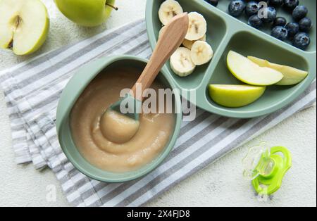 Alimenti sani per bambini nel recipiente. Pappe fruttate con mela e banana su sfondo bianco Foto Stock