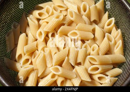Primo piano i maccheroni cotti sgocciolati in un setaccio in acciaio inox, filtro a rete. Maggio, Paesi Bassi Foto Stock