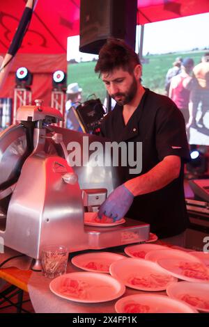 Macelleria che affetta un delizioso prosciutto al deli Foto Stock