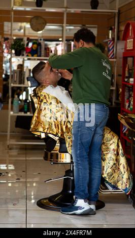 Barbiere che dà il taglio di capelli al cliente all'interno Foto Stock