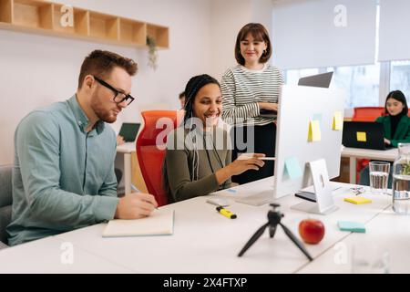 Colleghi multietnici positivi dipendenti che collaborano in ufficio parlano insieme sul posto di lavoro. Collaboratori di team di giovani startup diverse Foto Stock