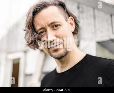 Ritratto di un uomo sorridente con i capelli lunghi Foto Stock