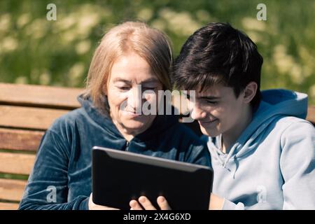 Donna anziana con suo nipote che usa la tecnologia moderna Foto Stock