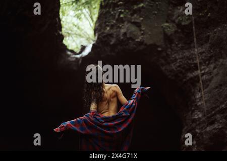 Una giovane donna indossa i vestiti dopo aver nuotato in una cascata. Foto Stock