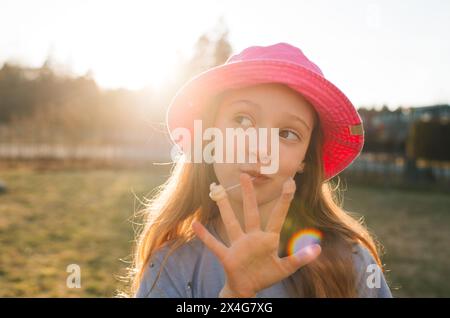 ragazza che crea facce con gomme al tramonto Foto Stock