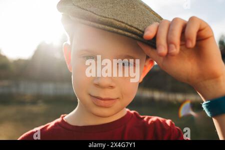 bel ragazzo che indossa un berretto piatto al tramonto Foto Stock