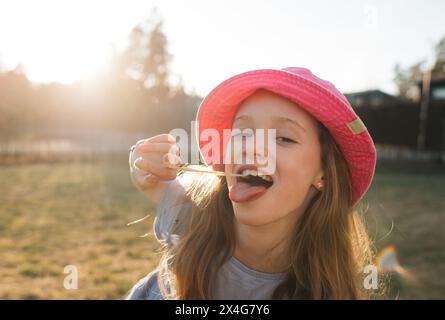 ragazza che crea facce con gomma frizzante in estate Foto Stock