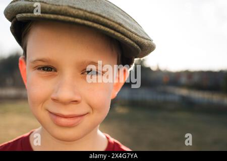 primo piano ritratto di un ragazzo con un berretto piatto al tramonto Foto Stock