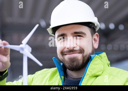 ingegnere maschio con casco e barba con un modello di mulino a vento Foto Stock