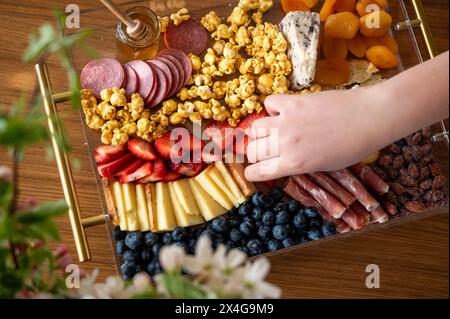 Mano che cerca il cibo da una bella tavola di salumi Foto Stock