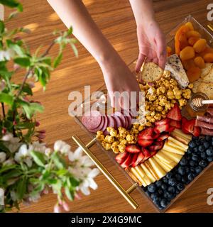 Mani che cercano cracker da un delizioso tagliere di salumi Foto Stock