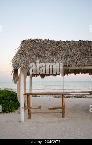 Due altalene vuote sotto un tetto di paglia sulla spiaggia di Mexi Foto Stock