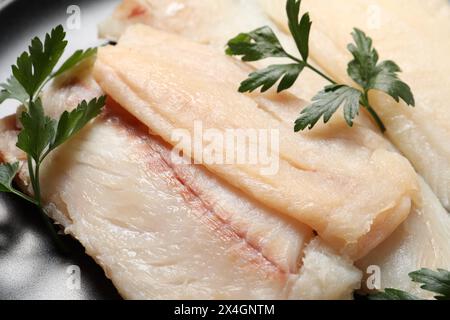 Merluzzo crudo e prezzemolo sul piatto, primo piano Foto Stock