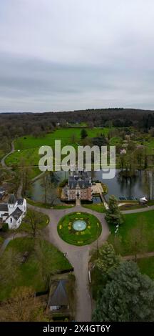 Huizingen, Belgio, 26 marzo 2024, questa immagine offre una prospettiva aerea del dominio di Huizingen, una grande tenuta in Belgio, sullo sfondo di ampi giardini e aree boschive. L'edificio principale, un maestoso maniero, si riflette nelle calme acque di un laghetto circostante. I prati ben curati e il giardino ornamentale della meridiana mostrano l'eleganza storica e la bellezza naturale della tenuta. Vista aerea del maestoso dominio Huizingen in Belgio. Foto di alta qualità Foto Stock