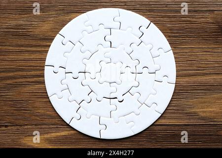 Puzzle circolare vuoto disposto su uno sfondo di legno con spazio per le copie. Foto Stock