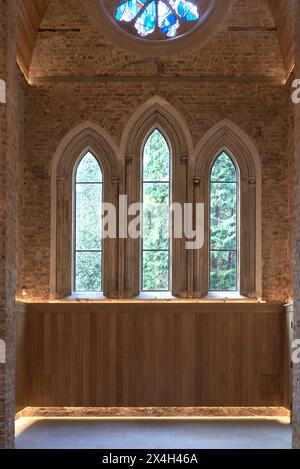 Finestra gotica ad arco con vista sul cimitero. Abney Park Chapel, Londra, Regno Unito. Architetto: Kaner Olette Architects, 2023. Foto Stock