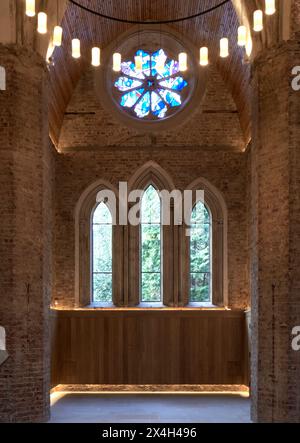 Finestra gotica ad arco con vista sul cimitero. Abney Park Chapel, Londra, Regno Unito. Architetto: Kaner Olette Architects, 2023. Foto Stock