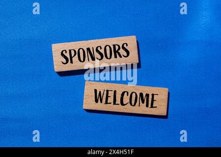 Gli sponsor accolgono le parole scritte su blocchi di legno con sfondo blu. Simbolo commerciale concettuale. Copia spazio. Foto Stock