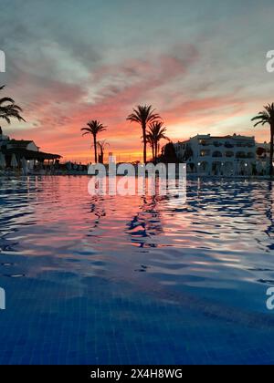 riflessi del tramonto: le vivaci sfumature di rosso e arancione del sole che tramonta danzano sulla superficie di una piscina tranquilla, creando uno splendido contrasto wi-fi Foto Stock