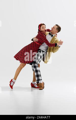 Elegante giovane coppia uomo e donna in un elegante abito d'epoca che danzava con danza retrò isolata su sfondo bianco dello studio Foto Stock