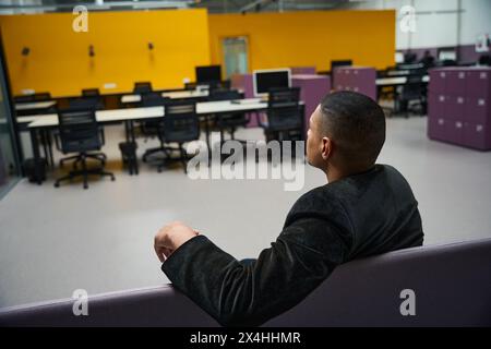 Uomo seduto ad aspettare qualcuno in un ufficio vuoto Foto Stock