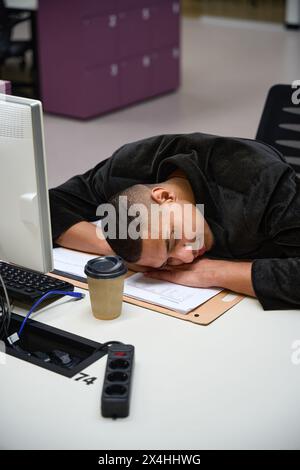 Uomo calmo che dorme mentre sdraiato sul tavolo in ufficio Foto Stock