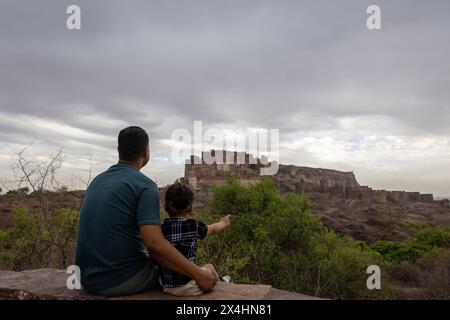 padre con figlio neonato che guarda il forte storico al nuvoloso giorno immagine viene scattata a mehrangarh jodhpur rajasthan india. Foto Stock