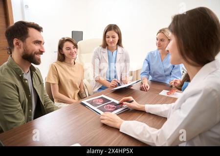 Riunione ginecologica che esamina i risultati della scansione ecografica di una giovane donna incinta Foto Stock