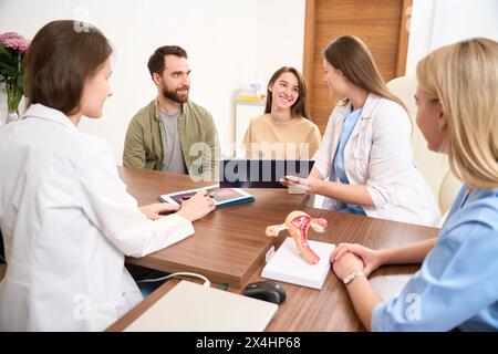 Riunione medica che esamina i risultati di esame giovane donna caucasica incinta Foto Stock