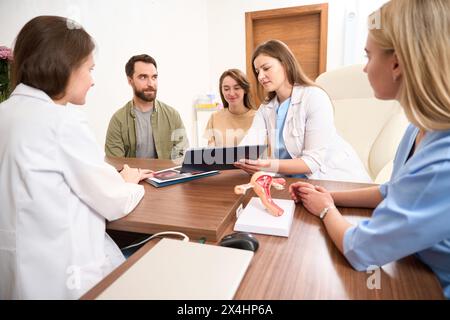 Riunione medica di medici che esaminano i risultati di esame di paziente donna incinta Foto Stock