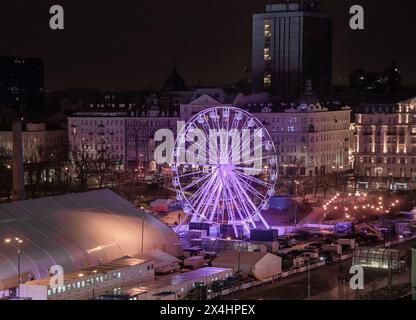 Warszawa, Polonia - gennaio 30: Ruota panoramica illuminata con luci viola sullo skyline notturno della vivace città, sfondo Foto Stock