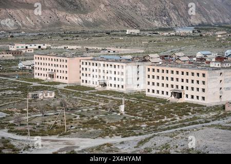 Edifici abbandonati in un paesaggio arido, città fantasma di Enilchek nei monti Tien Shan, Ak-su, Kirghizistan Foto Stock