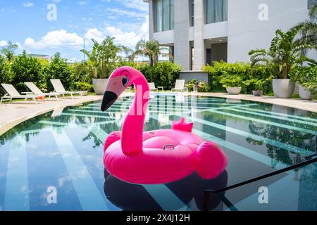 Un galleggiante rosa della piscina flamingo galleggia in una piscina Foto Stock