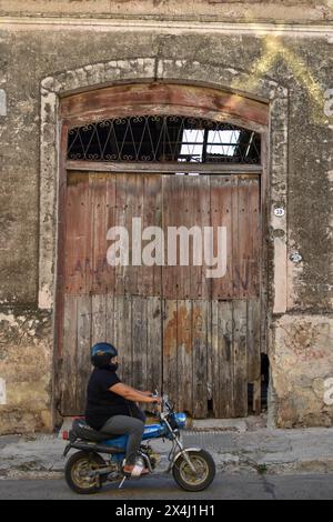 Donna grassa su un ciclomotore di fronte a un vecchio magazzino, scena rurale a Victoria, Duck, Argentina Foto Stock