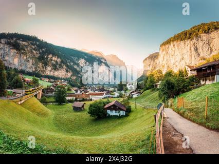 Vista panoramica della valle di Lauterbrunnen con villaggio rustico, famosa chiesa e cascate di Staubbach durante la fine dell'estate al mattino a Berna, Svizzera Foto Stock