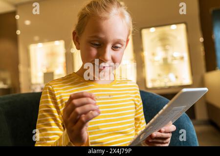 Giovane ragazza sorridente e concentrata su un'esibizione audace per scegliere il suo preferito in una gioielleria Foto Stock