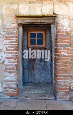 Porta di legno molto vecchia e usurata in mattoni di adobe Foto Stock