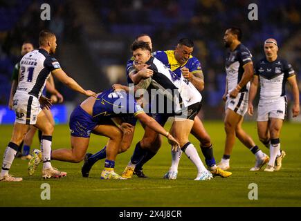 Tom Briscoe (centro) degli Hull FC è placcato da Paul Vaughan e Joe Philbin dei Warrington Wolves durante il Betfred Super League match all'Halliwell Jones Stadium di Warrington. Data foto: Venerdì 3 maggio 2024. Foto Stock