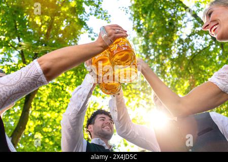 Gruppo di amici felici che bevono e tostano birra in costume tradizionale bavarese all'Oktoberfest, festival folcloristico o della birra, monaco, germania Foto Stock