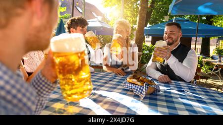 Amici seduti nel giardino della birra bavarese e gustatevi la birra e il sole Foto Stock